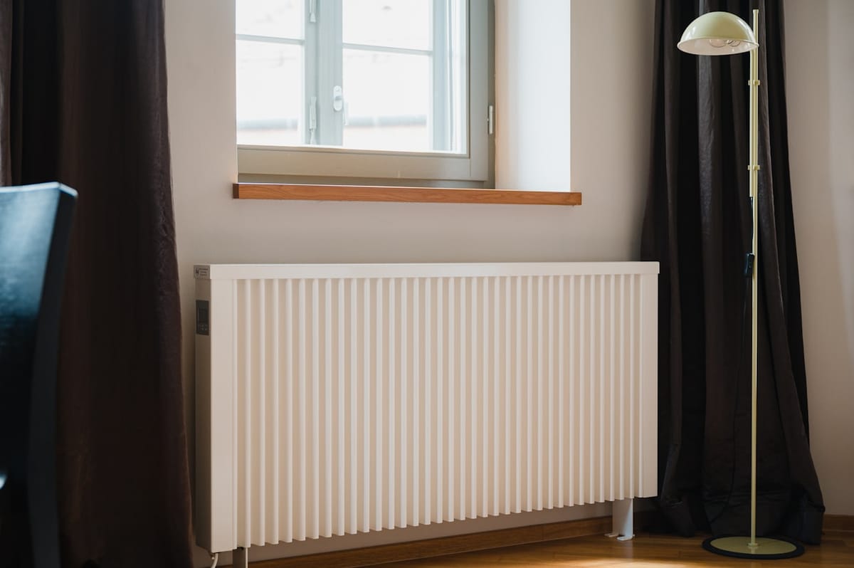 Hvid radiator under et vindue i en lys stue