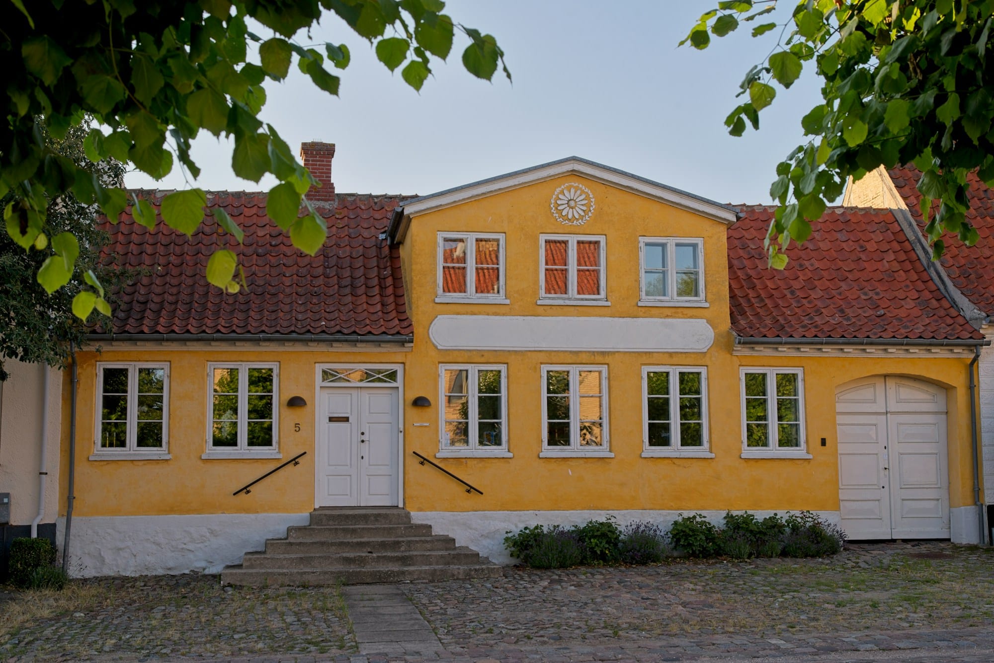 Ældre gult hus med rødt tegltag og hvide vinduer